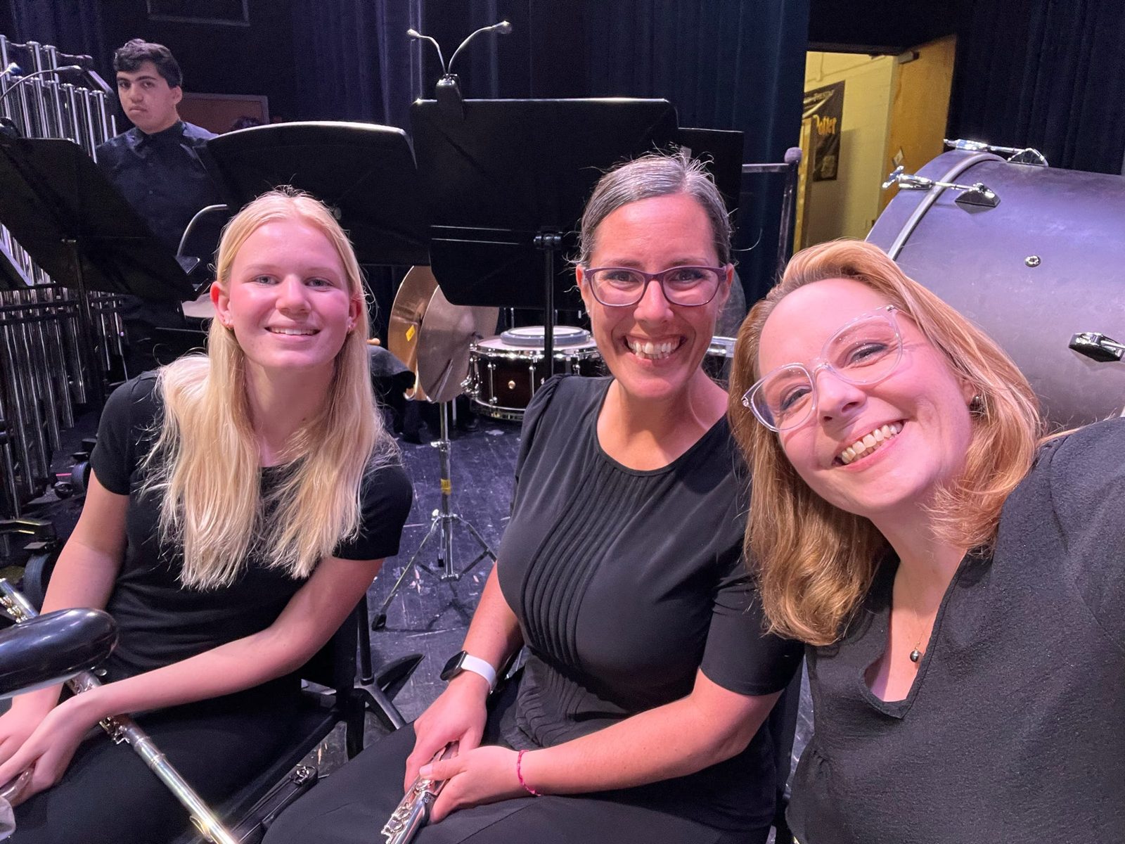 Three orchestra members smiling together before a performance